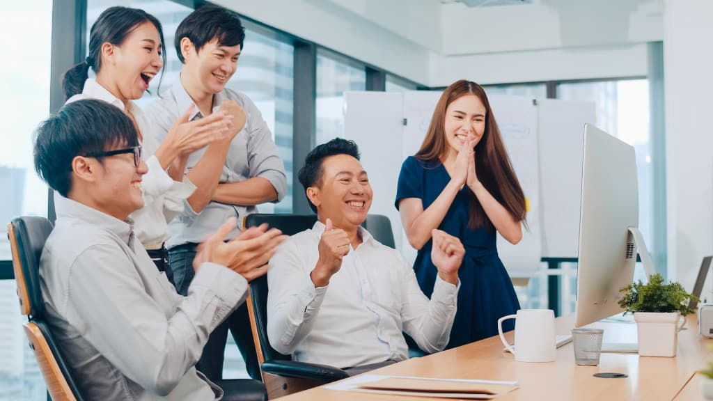 APAC business team celebrating a successful deal in a modern office
